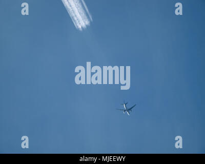 Aeroplano e chemtrails in cielo blu Foto Stock