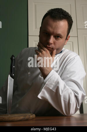 Chef in semi dark light ti guardano molto gravi (l'immagine viene wuth low key filter) Foto Stock