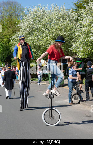 The Borough, Downton, Salisbury, Wiltshire, Regno Unito, 5th maggio 2018. Mayday festa week-end fiera di strada celebra l'arrivo di primavera Un camminatore palafitte e mono ciclista bilanciamento nella parata. Foto Stock