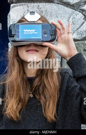 Donna che indossa la realtà virtuale auricolare per visualizzare le Skellig Rocks, nella contea di Kerry, Irlanda dall' isola Valentia Visitor Center, organizza per Failte Ireland Tourism, durante il mese di maggio la quarta banca weekend di vacanza Foto Stock