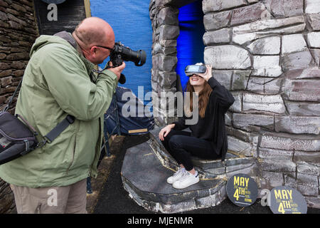 La donna che è fotografata indossando la realtà virtuale auricolare per visualizzare le Skellig Rocks, nella contea di Kerry, Irlanda dall' isola Valentia Visitor Center, organizza per Failte Ireland Tourism, durante il mese di maggio la quarta banca weekend di vacanza Foto Stock