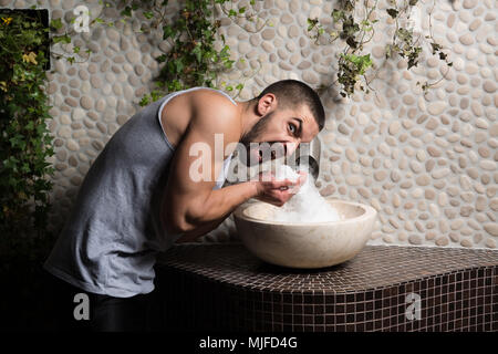 Happy Good Looking e attraente Giovane con corpo muscoloso relax nella sauna con organici bianco Himalayan Rock Salt Spa Foto Stock