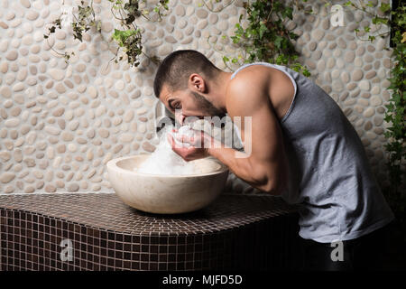 Happy Good Looking e attraente Giovane con corpo muscoloso relax nella sauna con organici bianco Himalayan Rock Salt Spa Foto Stock