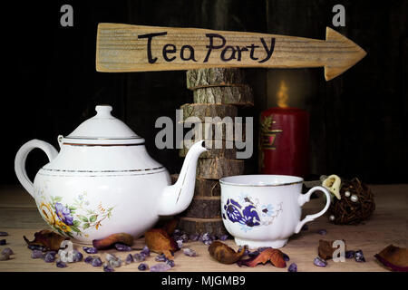 Tea Party. Tazza di tè e teiera sul tavolo di legno con segno di freccia in background Foto Stock