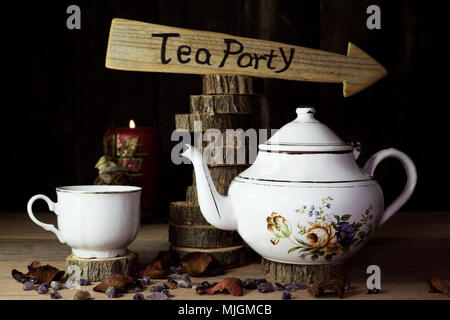 Tea Party. Tazza di tè e teiera sul tavolo di legno con segno di freccia in background Foto Stock