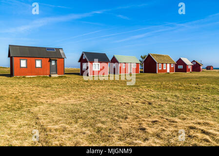 Kapelludden su Oland, Svezia. Rosso pesca in legno cabine in una fila lungo la costa. Foto Stock