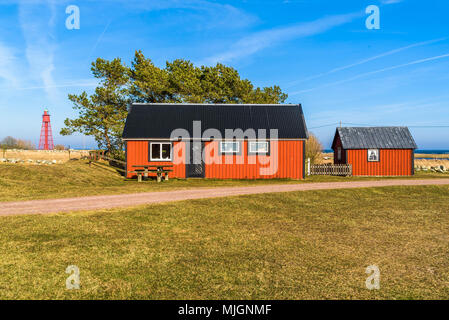 Kapelludden su Oland, Svezia. Rosso vacanza in legno cabina con capannone nel paesaggio costiero su una soleggiata giornata di primavera. Foto Stock