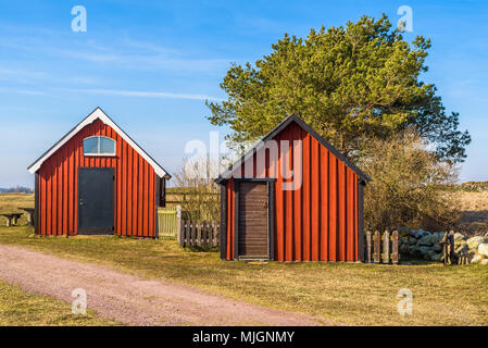 Kapelludden su Oland, Svezia. Rosso vacanza in legno cabina con capannone nel paesaggio costiero su una soleggiata giornata di primavera. Foto Stock