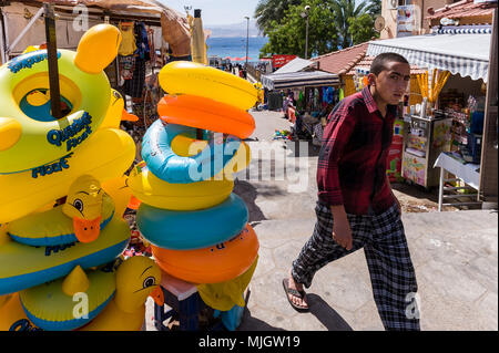 Ragazzo giovane a piedi lungo un negozio swimgear in Aqaba,una giordana città costiera situata alla punta nord-orientale del Mar Rosso. Foto Stock