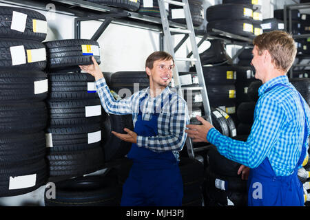Due colleghi concentrato il lavoro con i pneumatici per motocicli in punto di servizio Foto Stock