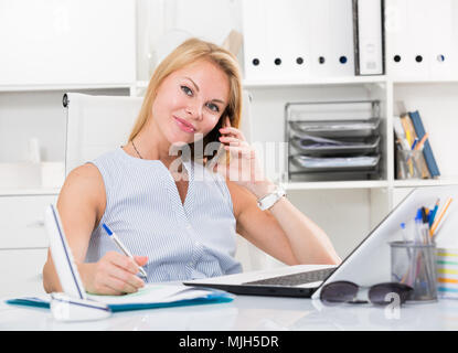 Ritratto di sorridente bionda ukraina ragazza per adulti in office talk sul telefono Foto Stock