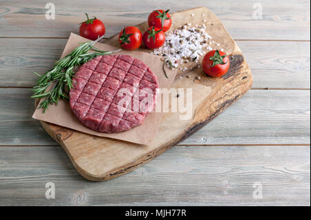 Cotolette di hamburger di carne fresca macinata con spezie fine erbe su una tavola di legno Foto Stock