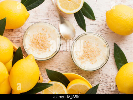 Vaso di vetro con Cheesecake al limone con limoni freschi su sfondo di legno Foto Stock