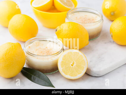 Vaso di vetro con Cheesecake al limone con limoni freschi su Sfondo marmo Foto Stock