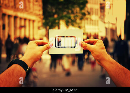 Man mano tenendo un foglio di carta bianco con l'icona della batteria scarica all'interno isolato su una strada affollata dello sfondo. Imprenditore concetto energetico, sensazione di stanchezza Foto Stock