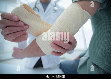 Ortopedico applicando un bendaggio sulla mano del paziente in clinica Foto Stock