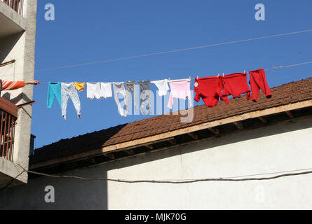 Abiti colorati vengono essiccati su una corda al di fuori su un cielo blu sullo sfondo. Servizio lavanderia è essiccata su una luce del sole . Lavavano i panni appesi all'aperto. Colore cont Foto Stock