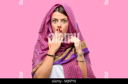 Giovane donna araba indossa hijab copre bocca in stato di shock, guarda timido, esprimendo il silenzio e confondere i concetti, paura Foto Stock