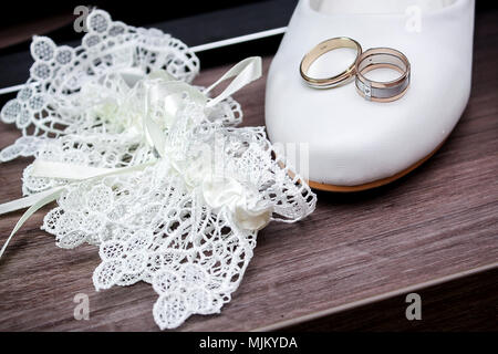 Nozze. Il decor. Sposa scarpe, un bellissimo mazzo di nozze, anelli, boutonniere e gioielli sono splendidamente steso su un grigio Sfondo di legno. Top v Foto Stock