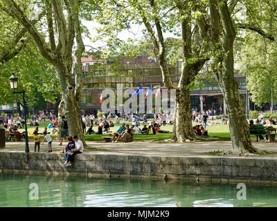 Masse di persone rilassarsi sul prato in un parco sul lago su un bel sabato pomeriggio a Annecy, Francia Foto Stock