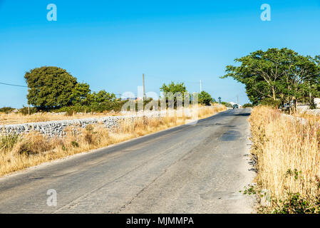 Guida auto su una vecchia strada tra i campi in estate in Sicilia, Italia Foto Stock