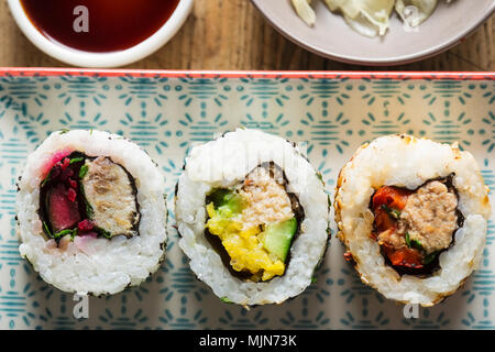 Sushi - California roll con tonno, sgombro, granchio, pepe, barbabietole con salsa di soia e zenzero sott'aceto Foto Stock