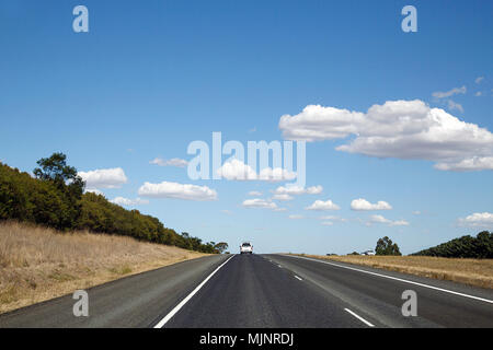 A seguito di una white pick up truck sull'autostrada nelle zone rurali dello Stato di Victoria - Australia. Il cielo blu con nuvole bianche. Foto Stock