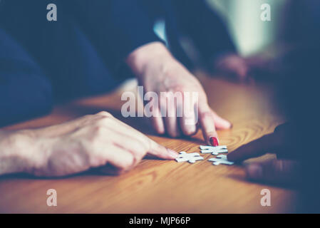 Le mani cercando di collegare il giovane pezzo di puzzle con sfondo, una parte della intera. il simbolo di associazione e connessione. strategia di business. Foto Stock