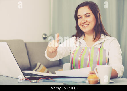 Giovane donna navigando attraverso utili suggerimenti per la cottura in Internet Foto Stock