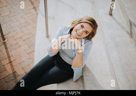 Carino femmina giovani musicisti amici ragazza ridere e cantare sulla città urbana Street passi al di fuori su di una bella giornata d'Autunno Foto Stock