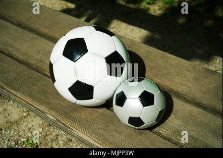 Due palloni da calcio su un parkbench in primavera Foto Stock