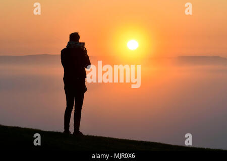 Glastonbury, Somerset, Regno Unito. Il 6 maggio 2018. Regno Unito Meteo. Visitatori Visualizza il sorgere del sole che è salita al di sopra di uno strato di nebbia dalla cima della collina al Glasonbury Tor in Somerset. Credito Foto: Graham Hunt/Alamy Live News Foto Stock