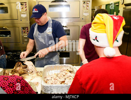 Centoventesimo Airlift Wing comando Master Chief Sgt. Steven Lynch intaglia una Turchia presso il centoventesimo Airlift Wing Dining Facility a Great Falls International Airport a Great Falls, Montana, 24 dic. 2017. Montana Air National Guard il personale si è offerto volontariamente per preparare 50 tacchini, spogliatoio e sugo di carne e consegnato il cibo per il Grande cade il centro anziani di essere servito durante la venticinquesima edizione del Danny Berg Memorial Cena di Natale. (U.S. Air National Guard foto/Senior Master Sgt. Eric Peterson) Foto Stock