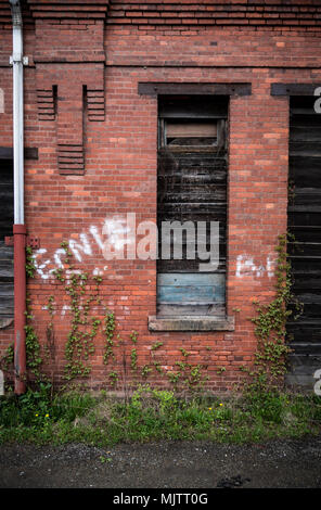 Esterno di una abbandonati, decadendo rosso mattone di edificio industriale Foto Stock