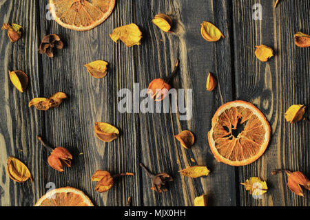 Fettine di arancia e petali di fiori secchi su sfondo di legno. Foto Stock