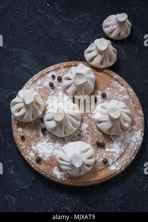 Pila di greggio in casa gnocchi di khinkali close up sulla pietra tavolo rustico. Foto Stock