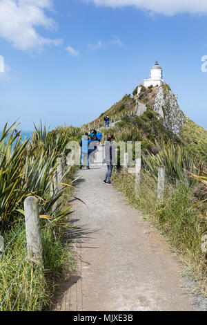 CATLINS COAST, NUOVA ZELANDA - 11 novembre 2017: i visitatori a piedi la via verso Nugget Point Lighthouse, una popolare attrazione turistica di Otago reg Foto Stock