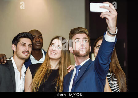 Gruppo di multi-etnico imprenditori di scattare una foto se stessi con un telefono cellulare dopo una riunione di affari Foto Stock