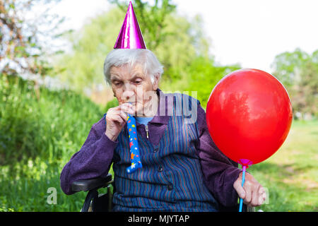 Donna anziana in una sedia a rotelle festeggia il compleanno nel parco Foto Stock