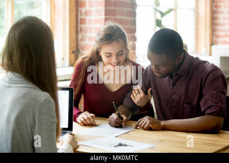 Multirazziale giovane firma di trattare da agente immobiliare Foto Stock