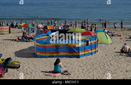 Le persone che si godono il sole in spiaggia Branksome, Poole, come per i fanatici del sole sono impostati a sizzle nella primavera canicola, con lunedì festivo previsioni per essere il più caldo da quando sono iniziate le registrazioni. Foto Stock