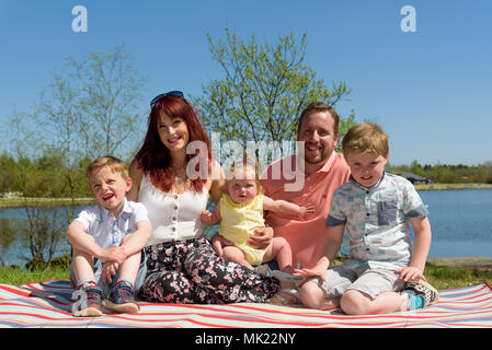 La famiglia di madre e padre di due figli e mia figlia da un lago in un pomeriggio soleggiato Foto Stock