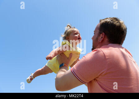 Felice gioiosa padre avendo divertimento getta in aria bambino .In movimento Foto Stock