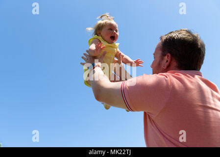 Felice gioiosa padre avendo divertimento getta in aria bambino .In movimento Foto Stock