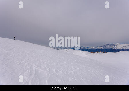 Alpinista solitario su una coperta di neve pendenza, con le vette delle Dolomiti in background, Copl Visentin, Belluno, Italia Foto Stock