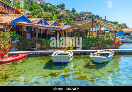 Il piccolo porto di pescatori con vecchie barche accanto al patio panoramico della costiera ristorante decorato con fiori luminosi in vasi, Kalekoy, Kekova, Tu Foto Stock