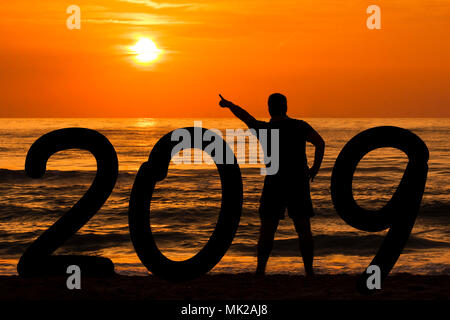 Silhouette uomo anno di formazione 2019 sottolineando sun all'alba in mare Foto Stock