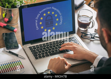 Il PILR UE. Uomo che lavora con un computer, generale della protezione dei dati il Regolamento e la bandiera dell'Unione europea sullo schermo Foto Stock