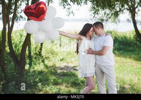 Felice e giovane coppia incinta abbracciando in natura. Momenti romantici Foto Stock