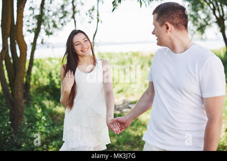 Felice e giovane coppia incinta abbracciando in natura. Momenti romantici Foto Stock